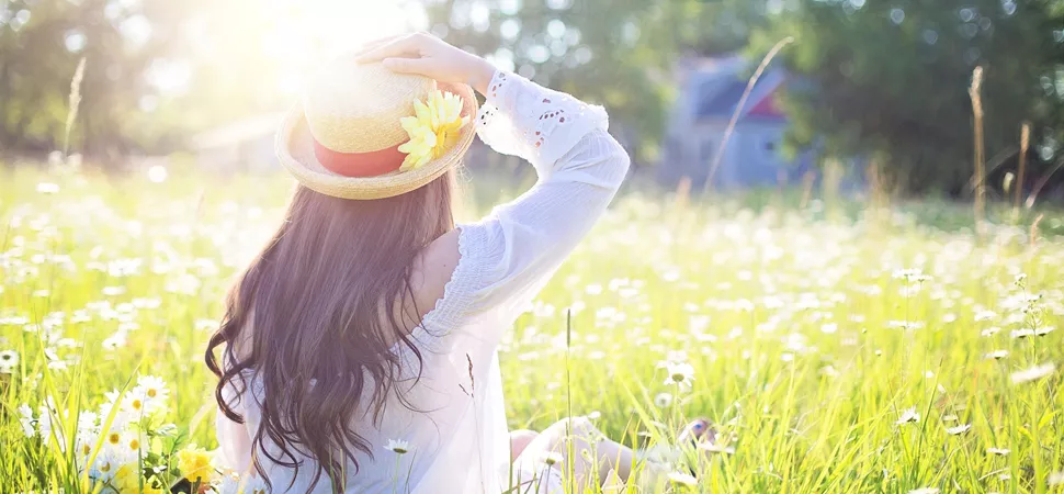 Frau genießt Sonnenstrahlen auf Blumenwiese