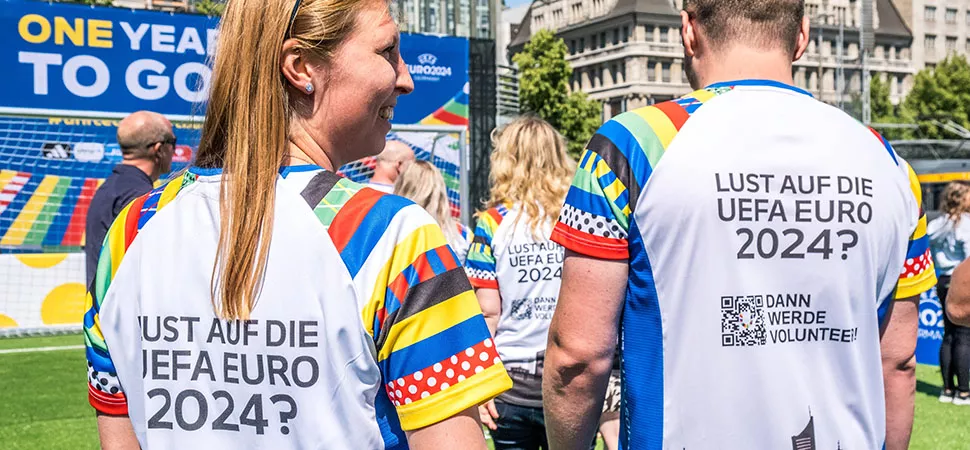 Eine Frau und ein Mann tragen Shirts auf deren Rücken "Lust auf die UEFA EURO 2024?" steht