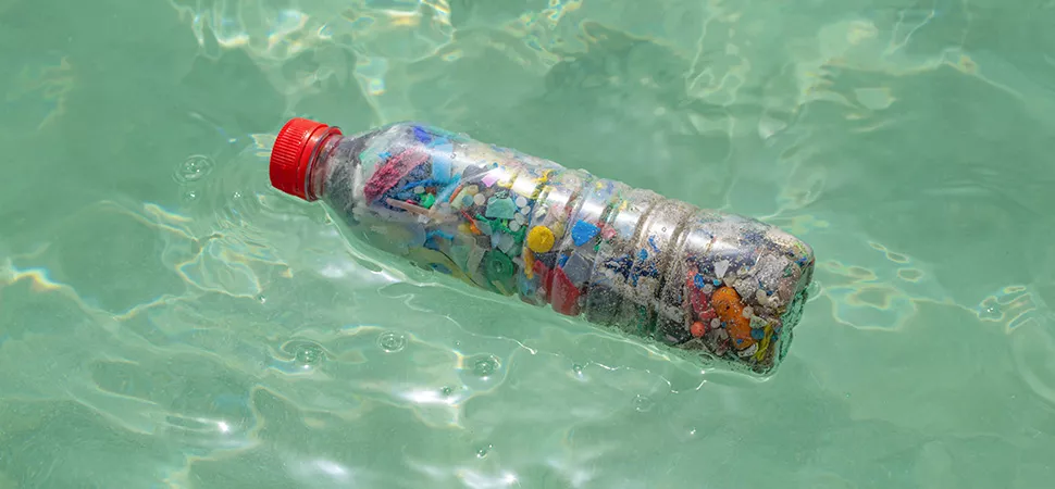 Mikroplastik in einer Plastikflasche, die im Wasser schwimmt