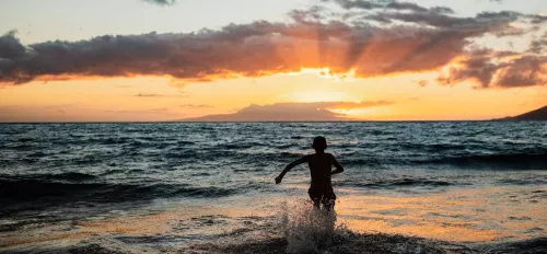 Junge rennt ins Meer beim Sonnenuntergang