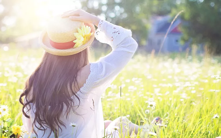 Frau genießt Sonnenstrahlen auf Blumenwiese